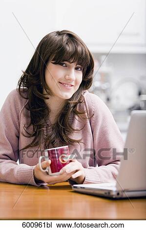 teenage girl sitting in kitchen in front of computer holding cup View Large Photo Image Stock Image - teenage girl sitting in kitchen in front of computer holding cup. Fotosearch