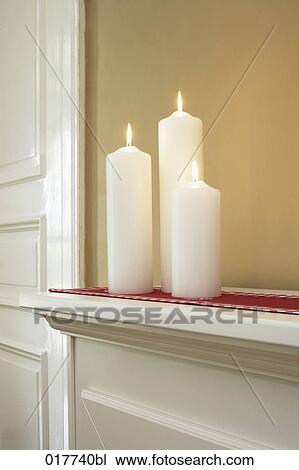 Stock Image - three candles burning in home. Fotosearch