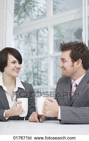 Stock Image - two business people sitting at table having break. Fotosearch