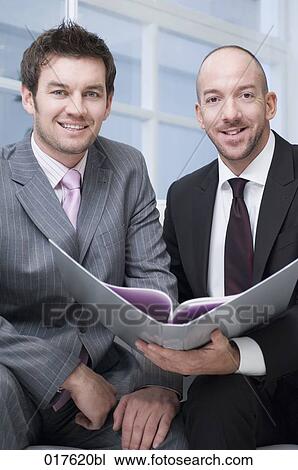 two businessmen sitting together reading document View Large Photo Image Stock Image - two businessmen sitting together reading document. Fotosearch