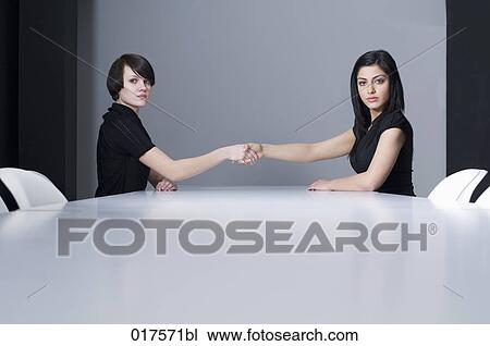 two businesswomen shaking hands at conference table View Large Photo Image Stock Image - two businesswomen shaking hands at conference table. Fotosearch