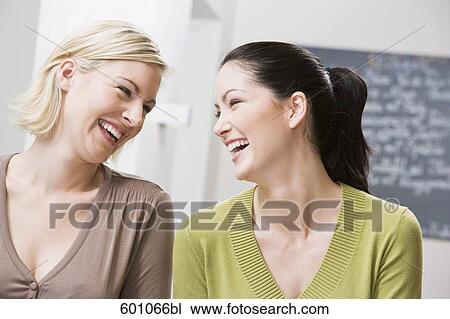 two female friends at restaurant happily laughing at each other View Large Photo Image Stock Image - two female friends at restaurant happily laughing at each other. Fotosearch