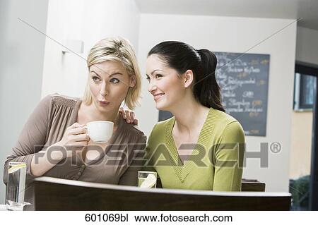 two female friends at restaurant whispering to each other View Large Photo Image Stock Image - two female friends at restaurant whispering to each other. Fotosearch