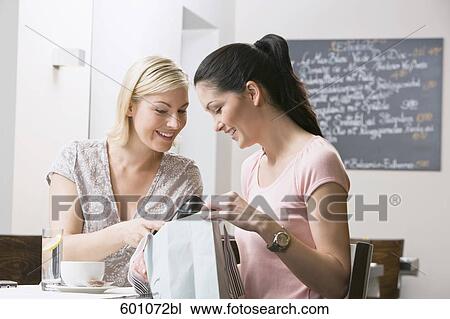 two female friends at restaurant looking at content of shopping bag View Large Photo Image Stock Image - two female friends at restaurant looking at content of shopping bag. Fotosearch