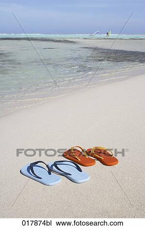 Stock Image - two pairs of flip flops on sandy beach. Fotosearch