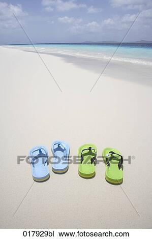 Stock Image - two pairs of flip flops on sandy beach. Fotosearch