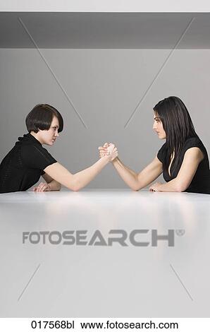 two young businesswomen doing arm wrestling at conference table View Large Photo Image Stock Image - two young businesswomen doing arm wrestling at conference table. Fotosearch