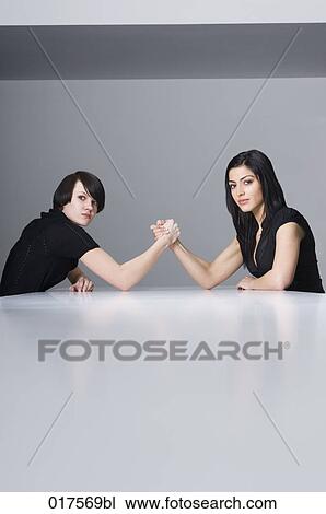 two young businesswomen doing arm wrestling at conference table View Large Photo Image Stock Image - two young businesswomen doing arm wrestling at conference table. Fotosearch