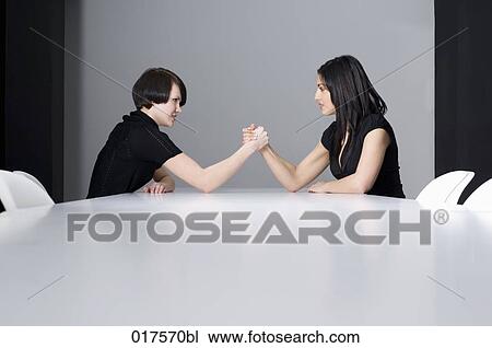 two young businesswomen doing arm wrestling at conference table View Large Photo Image Stock Image - two young businesswomen doing arm wrestling at conference table. Fotosearch
