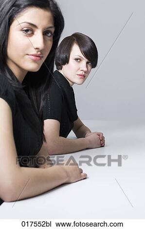 two young businesswomen sitting at conference table View Large Photo Image Stock Image - two young businesswomen sitting at conference table. Fotosearch