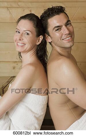 Stock Image - woman and man relaxing in sauna sitting back to back. Fotosearch