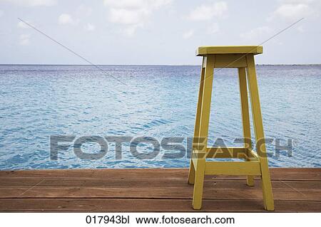 Stock Image - yellow stool on pier by the ocean. Fotosearch