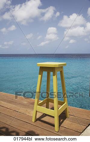 Stock Image - yellow stool on pier by the ocean. Fotosearch