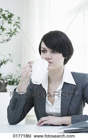 young businesswoman sitting at desk holding cup View Large Photo Image Stock Image - young businesswoman sitting at desk holding cup. Fotosearch