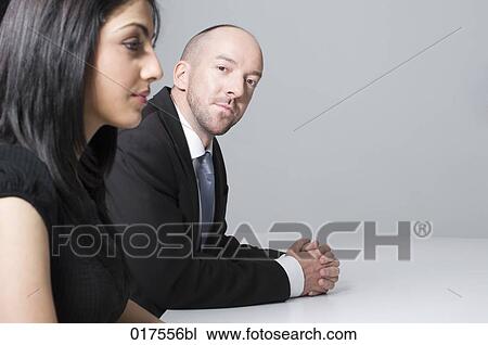 Stock Image - young businesswoman sitting at conference table with male colleague. Fotosearch