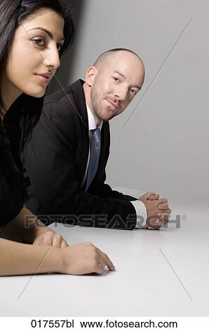 Stock Image - young businesswoman sitting at conference table with male colleague. Fotosearch