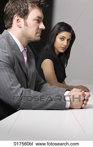 Stock Image - young businesswoman sitting at conference table with male colleague. Fotosearch