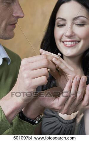 young couple at restaurant man putting ring on finger of woman View Large Photo Image Stock Image - young couple at restaurant man putting ring on finger of woman. Fotosearch