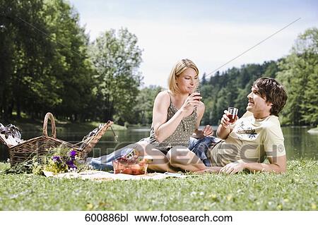 Stock Image - young couple having picnic in park. Fotosearch