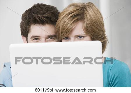 young couple hiding behind laptop computer View Large Photo Image Stock Image - young couple hiding behind laptop computer. Fotosearch