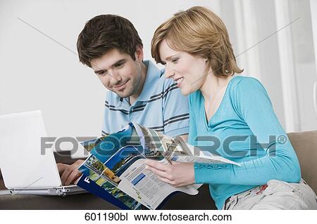 young couple in front of laptop computer looking at travel catalogue View Large Photo Image Stock Image - young couple in front of laptop computer looking at travel catalogue. Fotosearch