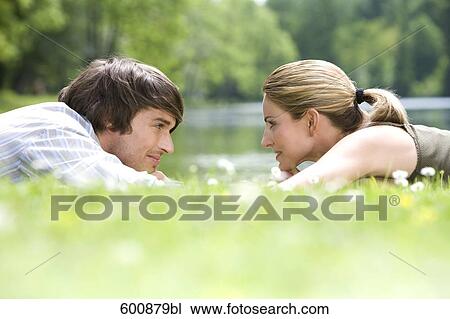 young couple lying in grass tenderly looking at each other View Large Photo Image Stock Image - young couple lying in grass tenderly looking at each other. Fotosearch