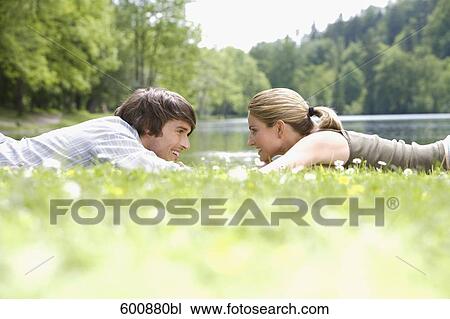 young couple lying in grass tenderly looking at each other View Large Photo Image Stock Image - young couple lying in grass tenderly looking at each other. Fotosearch