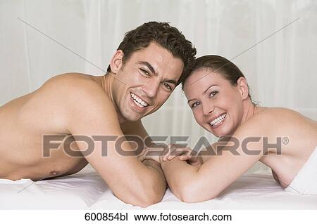 Stock Image - young couple lying on massage bench smiling at camera. Fotosearch