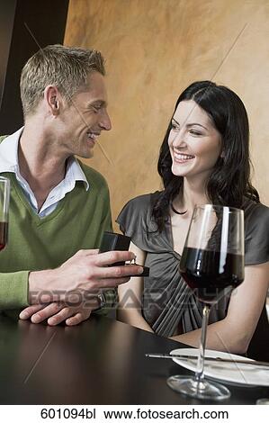 young couple sitting at restaurant man giving woman ring View Large Photo Image Stock Image - young couple sitting at restaurant man giving woman ring. Fotosearch