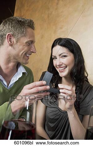 young couple sitting at restaurant man giving woman ring View Large Photo Image Stock Image - young couple sitting at restaurant man giving woman ring. Fotosearch