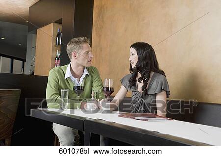 young couple sitting at restaurant with glasses of red wine View Large Photo Image Stock Image - young couple sitting at restaurant with glasses of red wine. Fotosearch