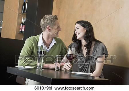 young couple sitting at restaurant with glasses of red wine View Large Photo Image Stock Image - young couple sitting at restaurant with glasses of red wine. Fotosearch