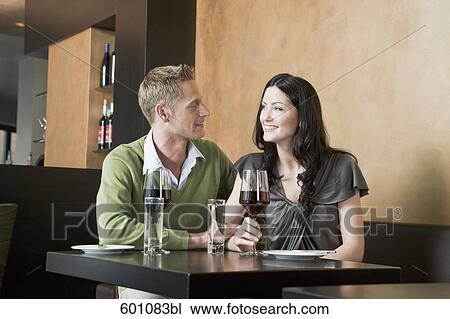 young couple sitting at restaurant with glasses of red wine View Large Photo Image Stock Image - young couple sitting at restaurant with glasses of red wine. Fotosearch