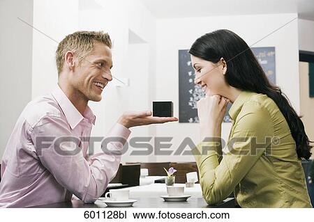 young couple sitting in cafe man presenting engagement ring to woman View Large Photo Image Stock Image - young couple sitting in cafe man presenting engagement ring to woman. Fotosearch
