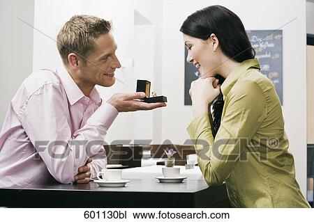young couple sitting in cafe man presenting engagement ring to woman View Large Photo Image Stock Image - young couple sitting in cafe man presenting engagement ring to woman. Fotosearch