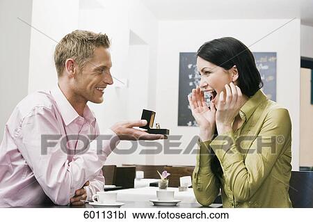 young couple sitting in cafe man presenting engagement ring to woman View Large Photo Image Stock Image - young couple sitting in cafe man presenting engagement ring to woman. Fotosearch