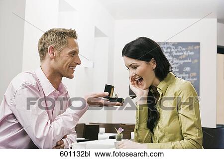 young couple sitting in cafe man presenting engagement ring to woman View Large Photo Image Stock Image - young couple sitting in cafe man presenting engagement ring to woman. Fotosearch