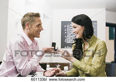 young couple sitting in cafe man presenting engagement ring to woman View Large Photo Image Stock Image - young couple sitting in cafe man presenting engagement ring to woman. Fotosearch