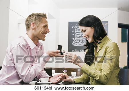 young couple sitting in cafe man presenting engagement ring to woman View Large Photo Image Stock Image - young couple sitting in cafe man presenting engagement ring to woman. Fotosearch