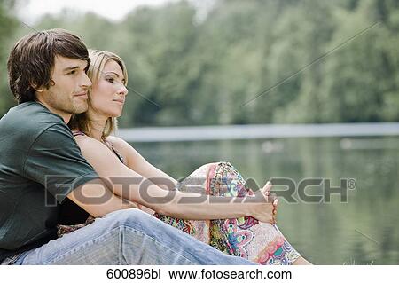 Stock Image - young couple sitting in tender embrace in park. Fotosearch