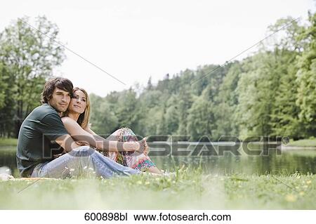 young couple sitting in tender embrace in park View Large Photo Image Stock Image - young couple sitting in tender embrace in park. Fotosearch