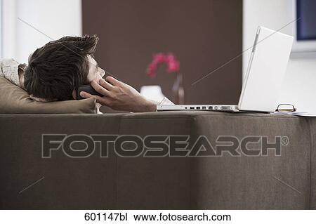 young man reclining on sofa and talking on mobile phone View Large Photo Image Stock Image - young man reclining on sofa and talking on mobile phone. Fotosearch