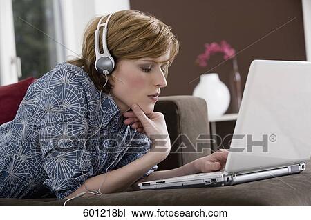 young woman at home wearing headset while working with laptop computer View Large Photo Image Stock Image - young woman at home wearing headset while working with laptop computer. Fotosearch