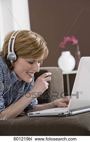 young woman at home wearing headset while working with laptop computer View Large Photo Image Stock Image - young woman at home wearing headset while working with laptop computer. Fotosearch