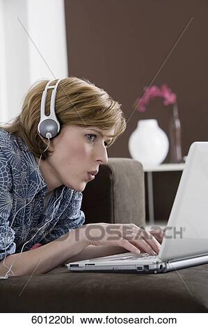 young woman at home wearing headset while working with laptop computer View Large Photo Image Stock Image - young woman at home wearing headset while working with laptop computer. Fotosearch