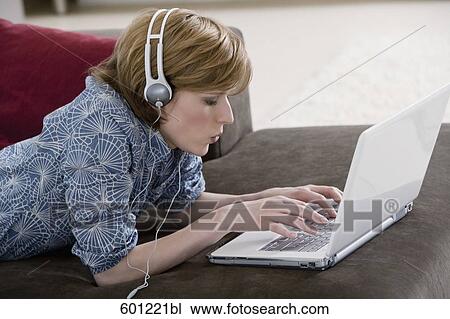 young woman at home wearing headset while working with laptop computer View Large Photo Image Stock Image - young woman at home wearing headset while working with laptop computer. Fotosearch