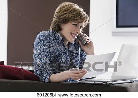 young woman at home with laptop computer talking on telephone View Large Photo Image Stock Image - young woman at home with laptop computer talking on telephone. Fotosearch