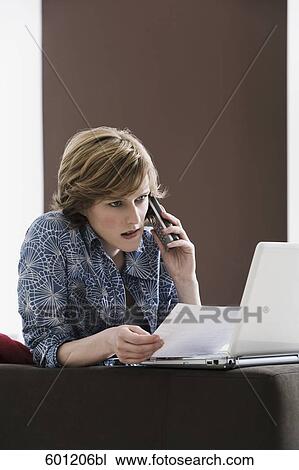 young woman at home with laptop computer talking on telephone View Large Photo Image Stock Image - young woman at home with laptop computer talking on telephone. Fotosearch