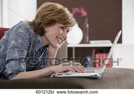 Stock Image - young woman at home working with laptop computer. Fotosearch