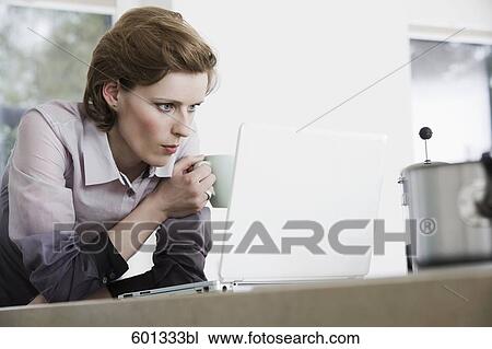 young woman at morning drinking coffee and looking at computer screen View Large Photo Image Stock Image - young woman at morning drinking coffee and looking at computer screen. Fotosearch